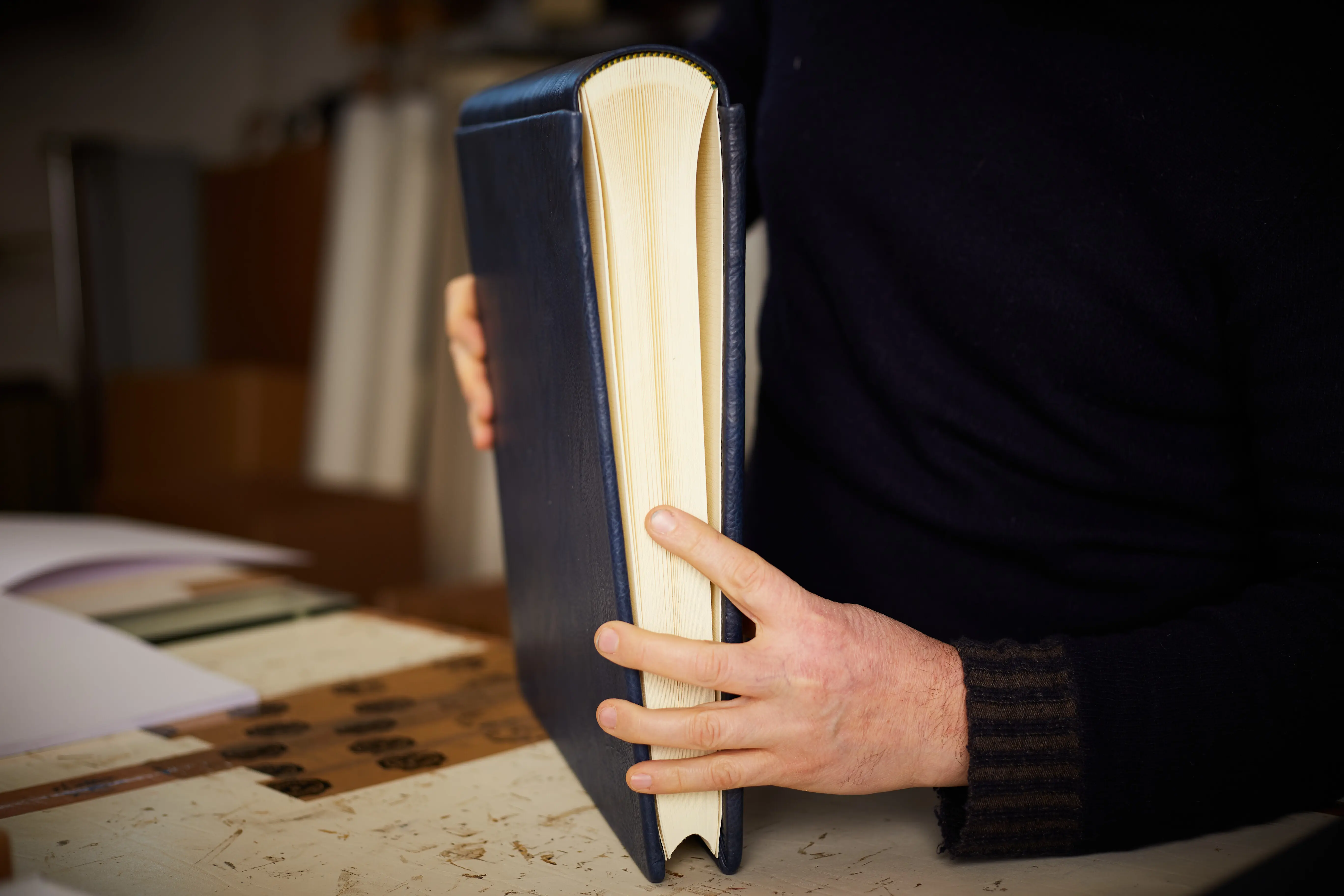 Mittlerer Körperbereich eines Mannes, der ein Buch auf dem Tisch hält